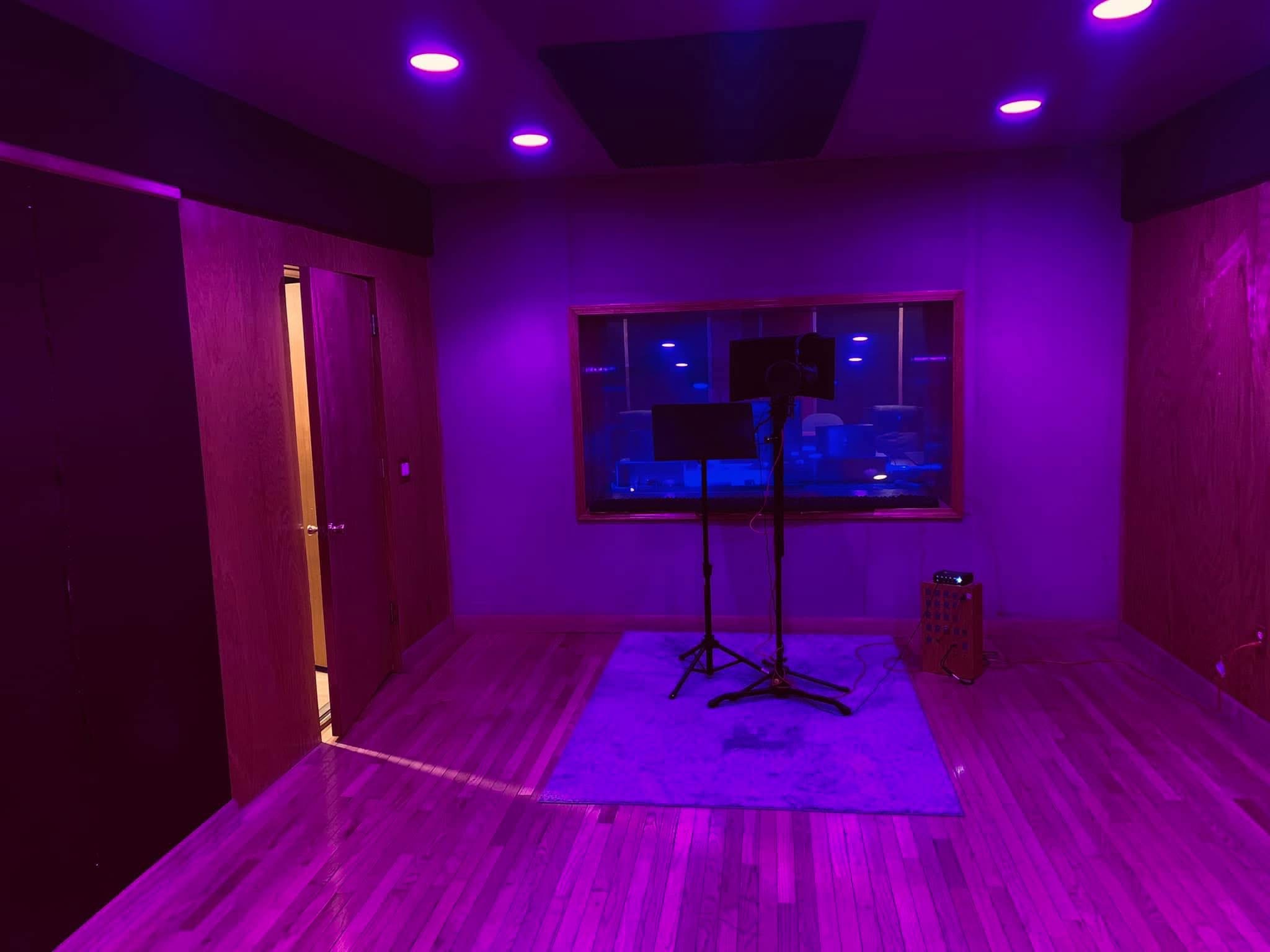 Included vocal booth with purple lighting, microphone and studio window